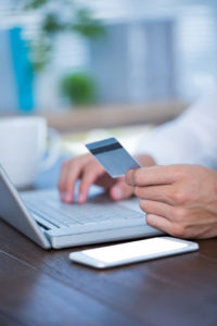 Close up view of a businessman using a credit card and typing
